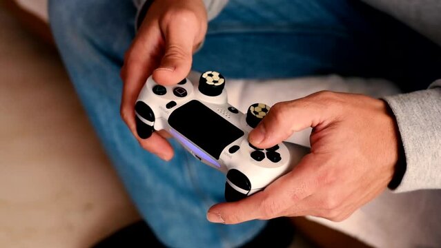 Close view of a gamer's hands playing simulator video game on console using joystick. 