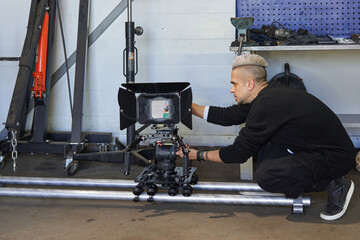 a videographer adjusts a professional movie camera standing on a camera trolley and rails in a hangar
