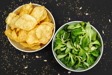 Fresh green organic lettuce leaves in a bowl and a bowl of chips. Healthy food and lifestyle