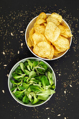 Fresh green organic lettuce leaves in a bowl and a bowl of chips. Healthy food and lifestyle