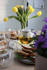 Indulge in an Elegant Afternoon Tea Time Selection - Enjoy a Beautifully Brewed Full Glass Teapot of Freshly Served Pastries and Refreshing Beverages, Adorned with Fresh Flowers and Tulips at a Beauti