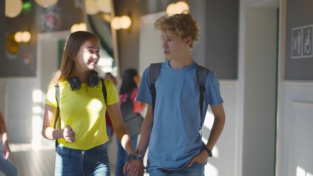 Two high school students, a boy and a girl, go to class holding hands. Realtime