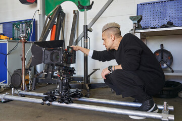 the cameraman on the set looks into the monitor of a professional movie camera. the video camera stands on the operator platform and rails