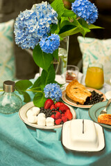 Nice breakfast in the summer garden. Coffee and sweets , fruits and flowers in a vase on the table .