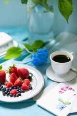 Nice breakfast in the summer garden. Coffee and sweets , fruits and flowers in a vase on the table .