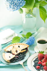 Nice breakfast in the summer garden. Coffee and sweets , fruits and flowers in a vase on the table .