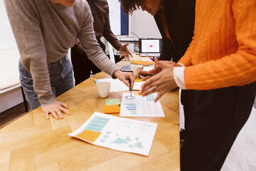 ollaborative Teamwork - Young Adults Working Together with Papers on Their Work Table, Engaging in Discussion with Gestures