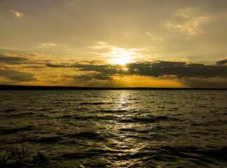Beautiful sunset. Orange sunset against the background of dark water. Delightful. golden sunset. A...