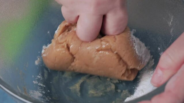 Women's hands knead the dough in a glass bowl for making homemade cookies. Close-up.