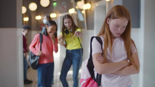 Teenagers pointing at red hair girl mocking nerd, verbal bullying. Realtime