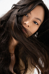 portrait of asian woman with shiny brunette hair looking at camera isolated on white.