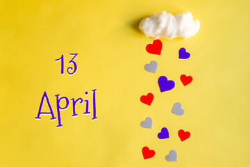 13 april day of month, colorful hearts rain from a white cotton cloud on a yellow background....
