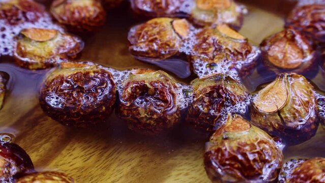 Brown dry soap nuts (Soapberries, Sapindus Mukorossi, Reetha) for organic laundry and gentle natural skin care circle rotation close up