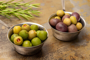 Dark and green olives in two metal bowls.