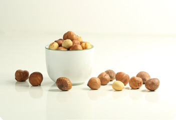 Obraz na płótnie Canvas Hazelnuts on white tableand in white cup , edible seed kernels, confectionery ingredient food