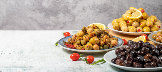 Olive varieties. Assortment of black and green olives on plate on gray background. Empty space for text. Copy space