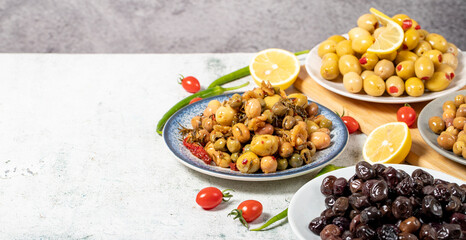 Olive varieties. Assortment of black and green olives on plate on gray background. Empty space for text. Copy space