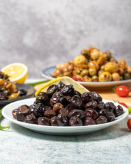 Olive varieties. Assortment of black and green olives on plate on gray background. low angle view