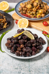 Olive varieties. Assortment of black and green olives on plate on gray background. Close up