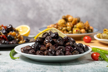 Olive varieties. Assortment of black and green olives on plate on gray background. low angle view