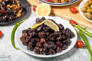 Olive varieties. Assortment of black and green olives on plate on gray background. Close up