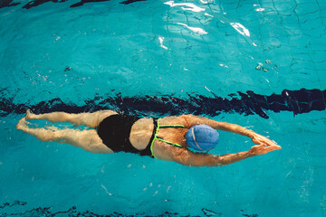 Woman swimming with swimming hat and swimsuit in swimming pool