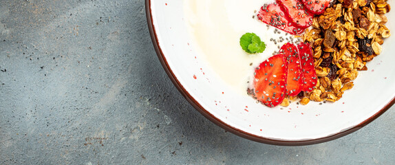 Granola with yogurt with fresh strawberry, chia seeds and honey on a gray background. Delicious balanced food concept. Long banner format. top view