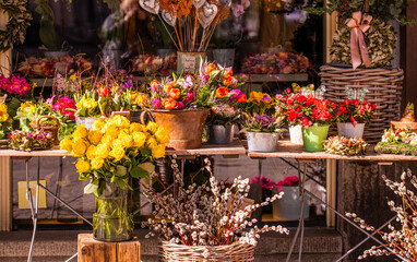 Fototapeta na wymiar Different flowers and seedlings near the florist flower shop entrance, spring time, easter concept