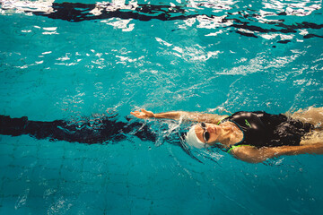 Woman swimming with swimming hat and swimsuit in swimming pool