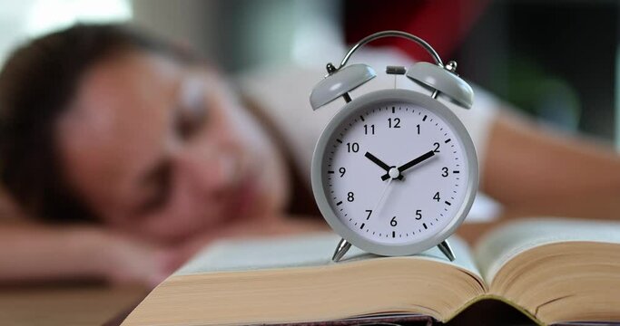 Woman sleeps with alarm clock and book