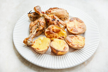 Chicken baked in pieces with potatoes and onion on a white dish. Home cooking. Healthy food, cooked without oil and salt.