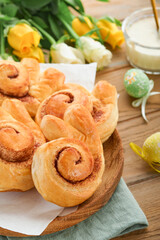 Easter breakfast Holliday concept. Easter bunny buns rolls with cinnamon made from yeast dough with orange glaze, easter decorations, colored eggs on old wooden background. Easter Holliday card.
