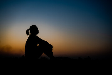 Fototapeta na wymiar Silhouette of a woman sitdown with so sad in the sunset.