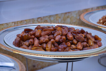 Close up of bowl full of ripped dates against blue background.
