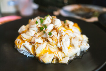 Crab omelette over rice, The fluffy omelette with chunks of fresh crab meat is placed on a mound of steamed rice and topped with sliced scallion. Chinese-influenced menu in Bangkok restaurant.