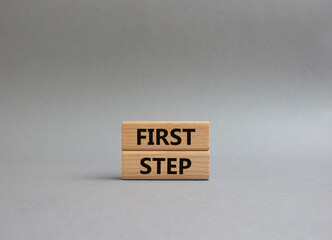 First step symbol. Wooden blocks with words First step. Beautiful grey background. Business and First step concept. Copy space.