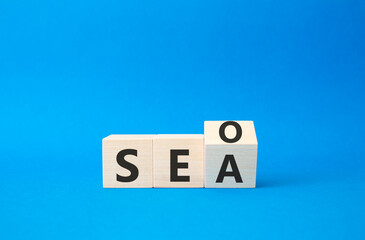 SEO vs SEA symbol. Turned wooden cubes with words SEA vs SEO. Beautiful blue background. Business and SEO vs SEA concept. Copy space
