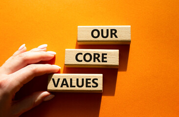 Our core values symbol. Concept words 'Our core values' on wooden blocks. Beautiful orange background. Businessman hand. Business and Our core values concept. Copy space.