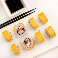 Sushi plate on white background, rolls set with cheese and tuna fish on white background from above. Top view of traditional japanese cuisine. Asian food with chopsticks design.