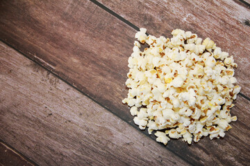 White fried popcorn on a brown wooden background