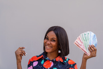Smiling African woman holding lots of money, on an isolated background