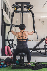 A short haired asian woman does a set of reverse pec deck flys at the gym. Focusing on the...