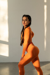 Sporty girl with an athletic body. Orange sports suit. Sunset