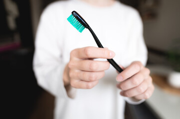 A woman's hand with a black and green toothbrush on a white background pulls a clean empty brush into the frame, a girl without a face