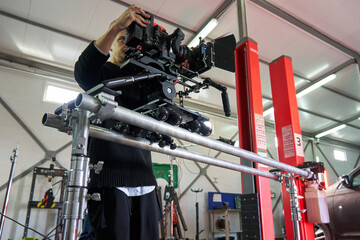 young caucasian cameraman installs a professional movie camera on a camera trolley on wheels on rails