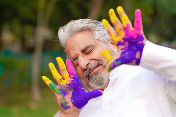 indian man giving scared expression between playing holi color. holi festival concept.