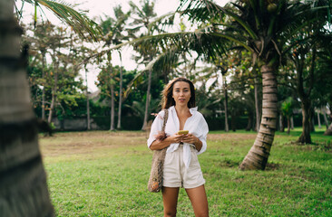 Naklejka premium Happy woman with smartphone standing in park
