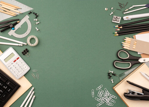 stationery items around of image on green background. Back to school background, banner with copy space. Student's or engineer's supplies. Office objects on dark green background. Calculator, keyboard