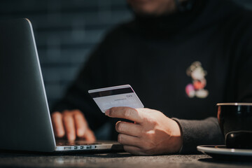 Online shopping, male hand holding credit card and using laptop at home.