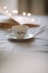 Light cozy bedroom, Coffee or tea cup and an open book on the bed. Spring still life. Breakfast in bed.